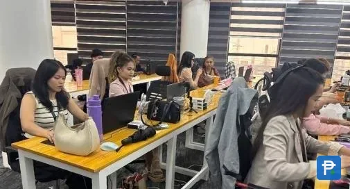 Staff working on laptops at rows of wooden desks in the Novaluxia office, a working space the platform shows publicly