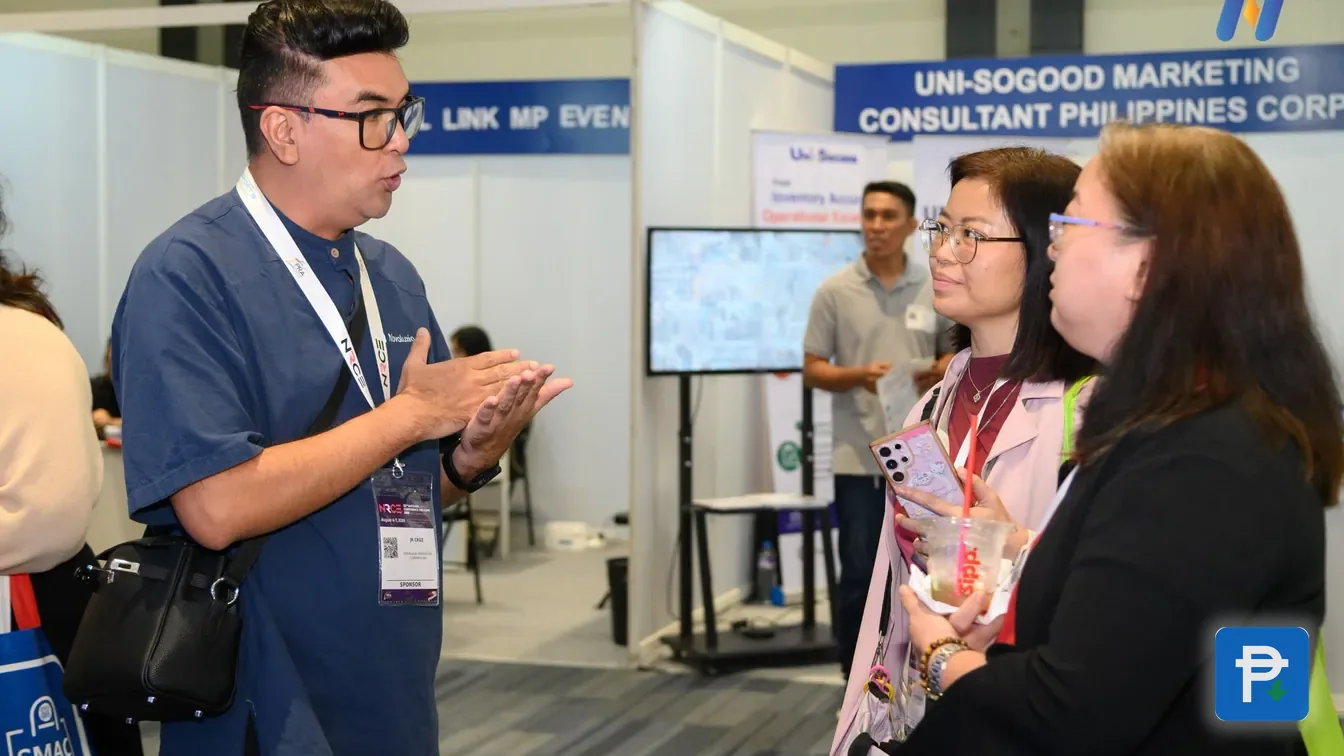 An exhibitor at a Novaluxia trade-show booth talking through the platform with two visitors
